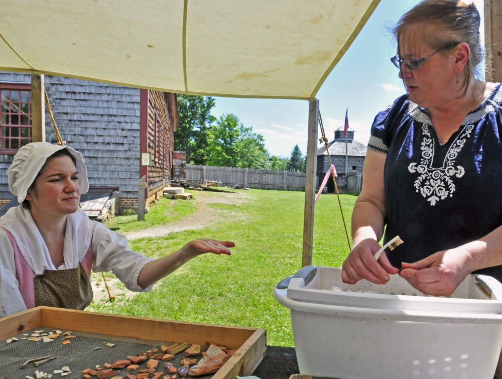 Historic interpreter Julia Pierce shows an artifact she has just cleaned to director Linda Novak at Old Fort Western in Augusta.
