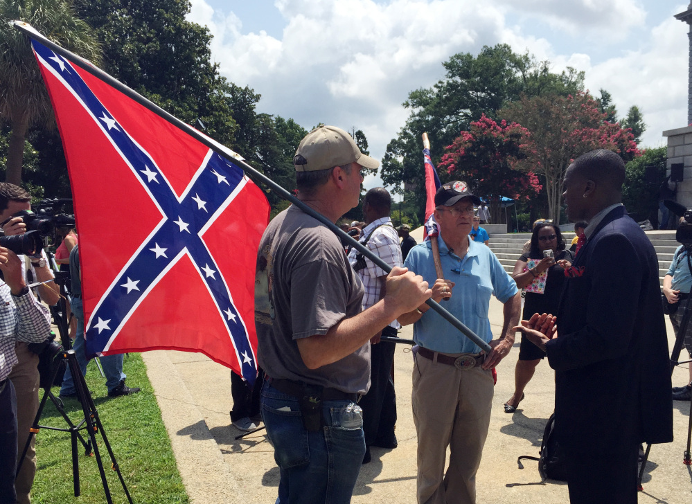 Randy Saxon, left and Wayne Whitfield, both of Anderson, S.C., discuss the Confederate flag on the South Carolina Statehouse grounds with Brodrick S. Hall of Atlanta, right, on Monday.