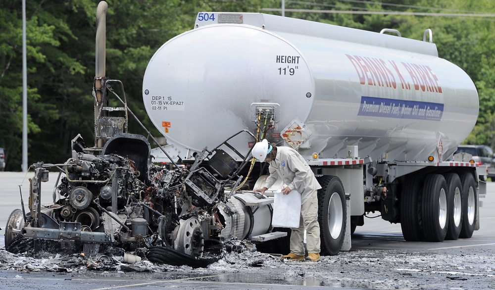 An agent with the Department of Environmental Protection inspects the damage and looks for spillage of diesel fuel after a fire demolished the cab of a tractor-trailer rig that had pulled into the Yarmouth commuter lot at exit 15 of I-295 on Wednesday.