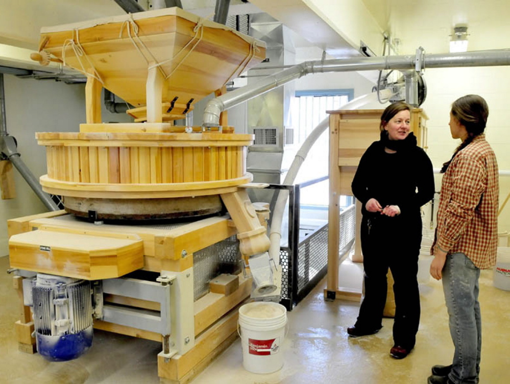Somerset Grist Mill owner Amber Lambke, left, and head miller Julie Zavage discuss an order being ground in the stone mill, far left. Lambke said the kosher certification is just one part of the healthy food production at the mill.