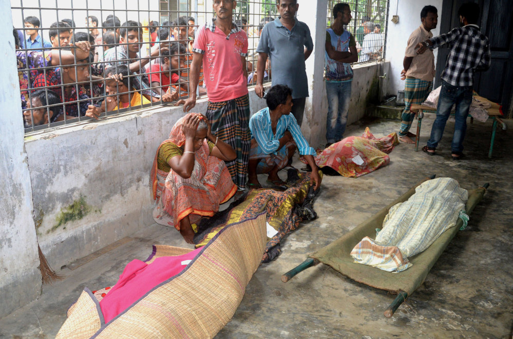 A woman, left, grieves beside bodies of stampede victims at Mymensingh Medical College Hospital in Mymensingh, Bangladesh, on Friday.