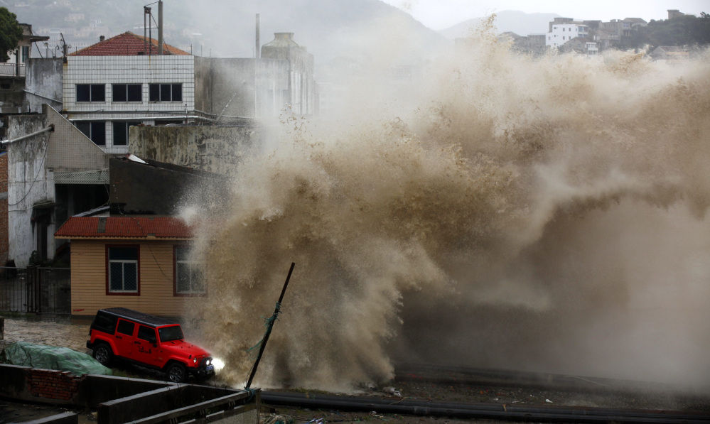 A massive wave breaks over a building and a vehicle ahead of the landfall of Typhoon Chan-hom in Wenling in eastern China’s Zhejiang province Friday. Chinese authorities canceled scores of trains and flights and shuttered seaside resorts as the typhoon with wind gusts up to 125 mph raced toward the southeastern coast.