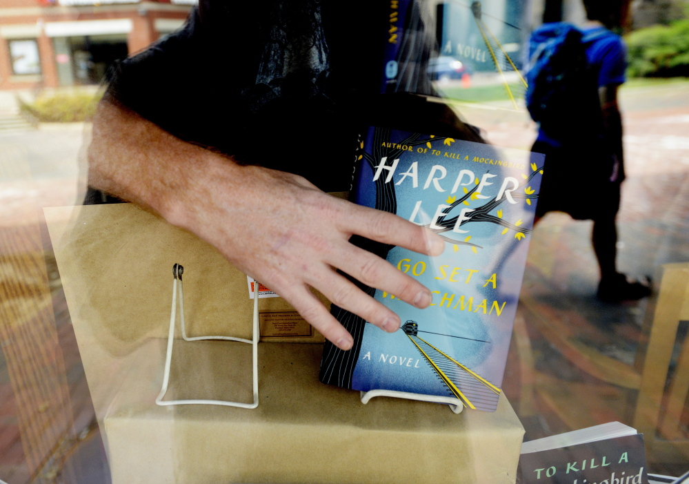 Bob Ulrich places Harper Lee’s latest novel in the display window Tuesday at Longfellow Books in Portland. The store in Monument Square ordered 200 copies of “Go Set a Watchman” and sold 50 in advance. Sherman’s Books & Stationery in the Old Port had about 100 copies.