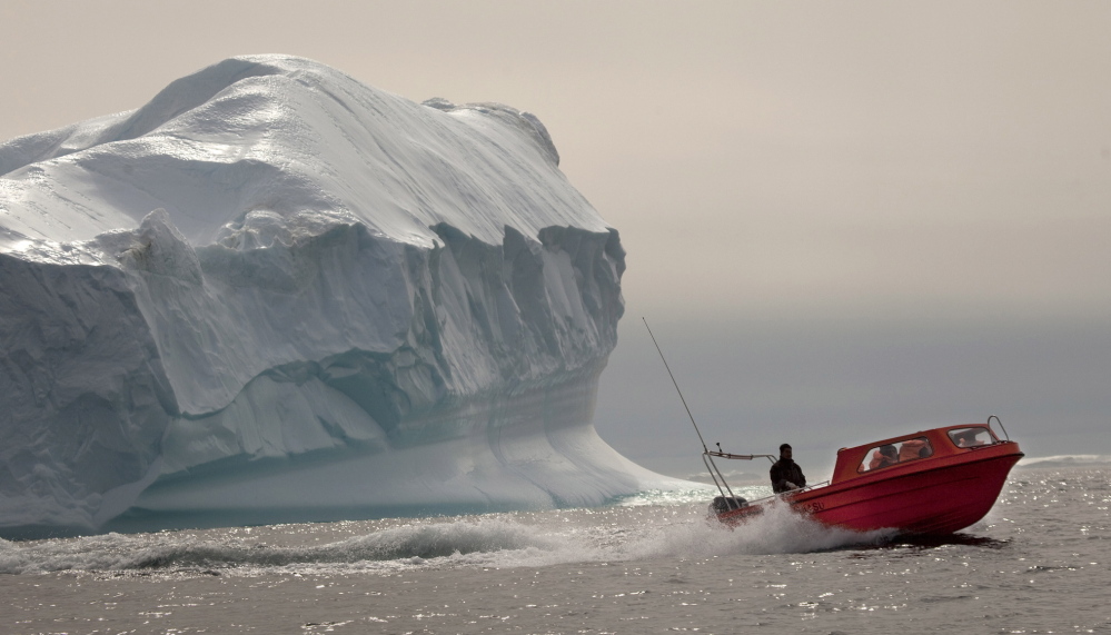 A boat carrying tourists speeds past an iceberg south of Tasiilaq in eastern Greenland.