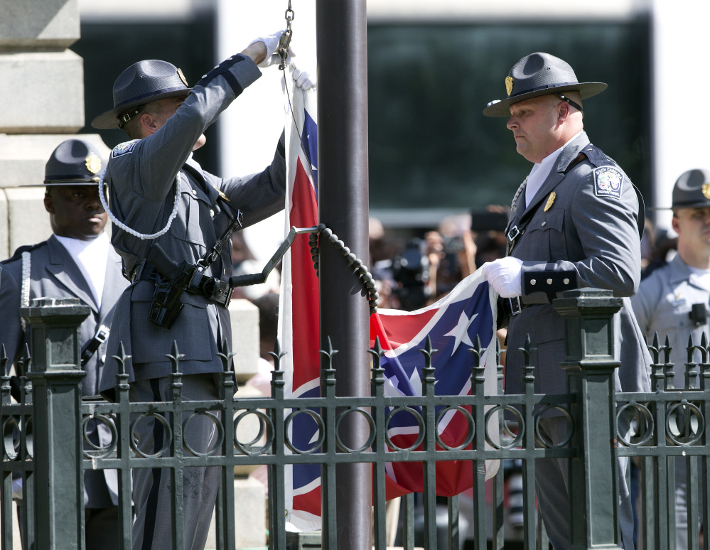 An honor guard from the South Carolina Highway Patrol lowers the Confederate battle flag as it is removed Friday from the Capitol grounds in Columbia, S.C. Legions of people clapped, cheered and cried as the flag came down.