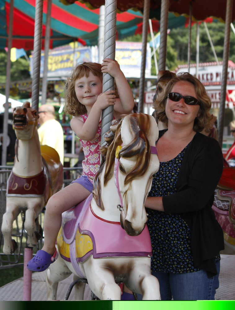 Jasmine Eagan, right, and her daughter Azalea, 4, ride on a carousel at the Yarmouth Clam Festival on Friday in Yarmouth. The carousel had been shut down after a malfunction earlier in the day.