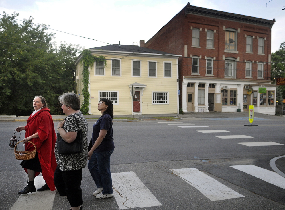 Kelly Henderson guides Lisa Hardman, center, of Alna, and Michelle Mason-Webber, of Farmingdale, through Hallowell on Wednesday. Henderson led the Red Cloak Tour of historic and haunted spots in the community.
