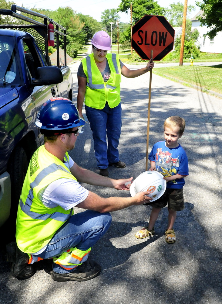 Ranger Corp. worker Jacob Flanagin shows Spencer Murray a union sticker on a hard hat given to the boy on Friday. Flagger Michelle Holmes watches.
