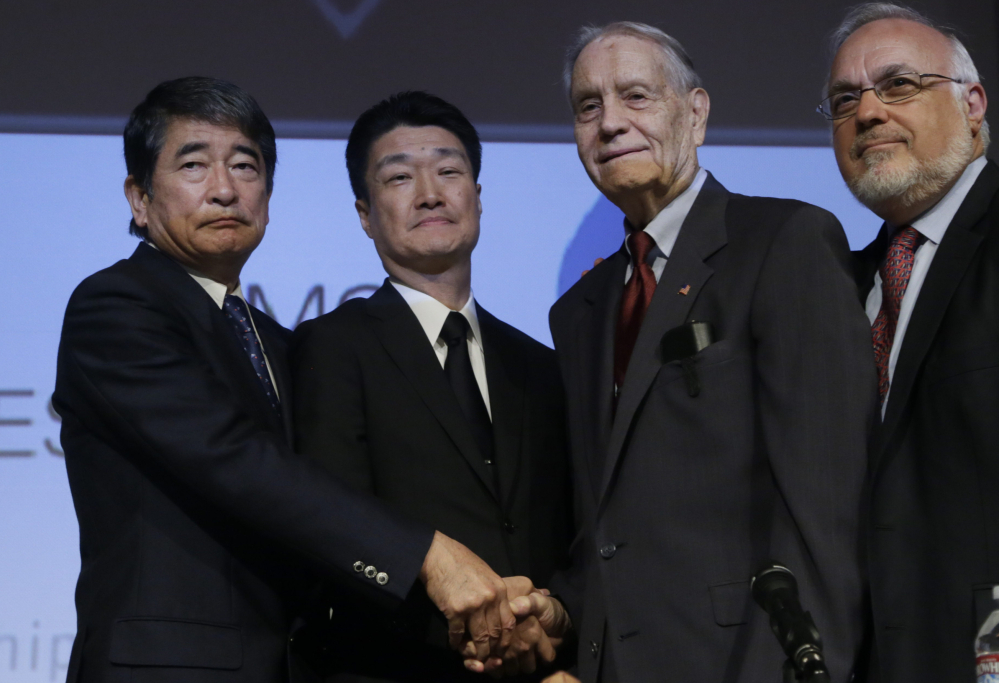 Mitsubishi Materials officials Yukio Okamoto, left, and Hikaru Kimura offer an apology as they hold hands with former U.S. prisoner of war James Murphy, 94, at the Simon Wiesenthal Center in Los Angeles on Sunday. Murphy said, “We can trust those words.”