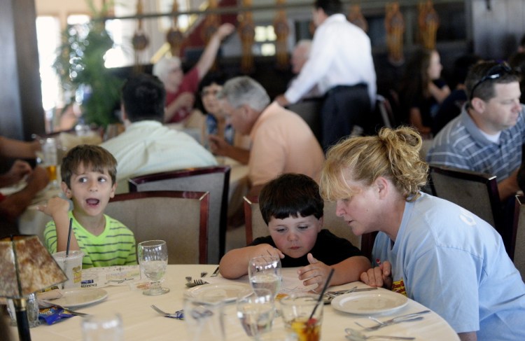 Laurie Joseph colors with her son Wyatt Holan, 4, sitting next to Joel Lamorte, 6, as the visitors from Pennsylvania wait for dinner Monday at DiMillo’s. Joseph said keeping kids busy at restaurants doesn’t always work, but staff should not yell at them.