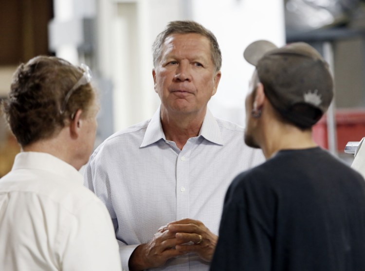In this July 13, 2015, file photo, Ohio Gov. John Kasich talks with Joshua Bowman, right, and Joe Shean during a visit at RP Abrasives in Rochester, N.H.