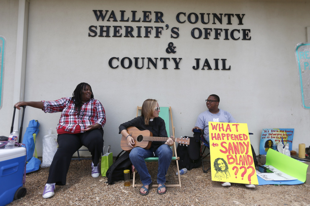 Carie Cauley, left, the Rev. Hannah Bonner and Rhys Caraway protest, after the death of Sandra Bland, as they sit in front of the Waller County Sheriff’s Office and county jail on Monday, in Hempstead, Texas.