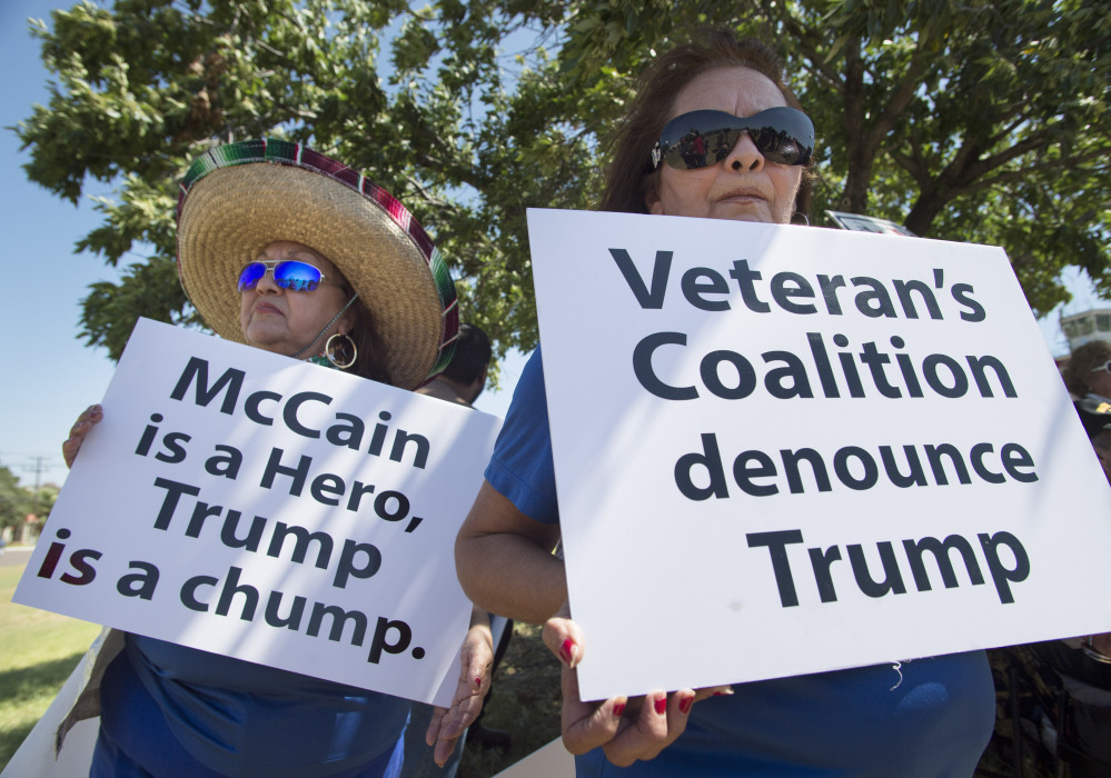 Lourdes Galvan, left, and Irma Vargas, both of San Antonio, Texas, hold signs denouncing Republican presidential contender Donald Trump on Thursday at Laredo International Airport in Laredo, Texas.