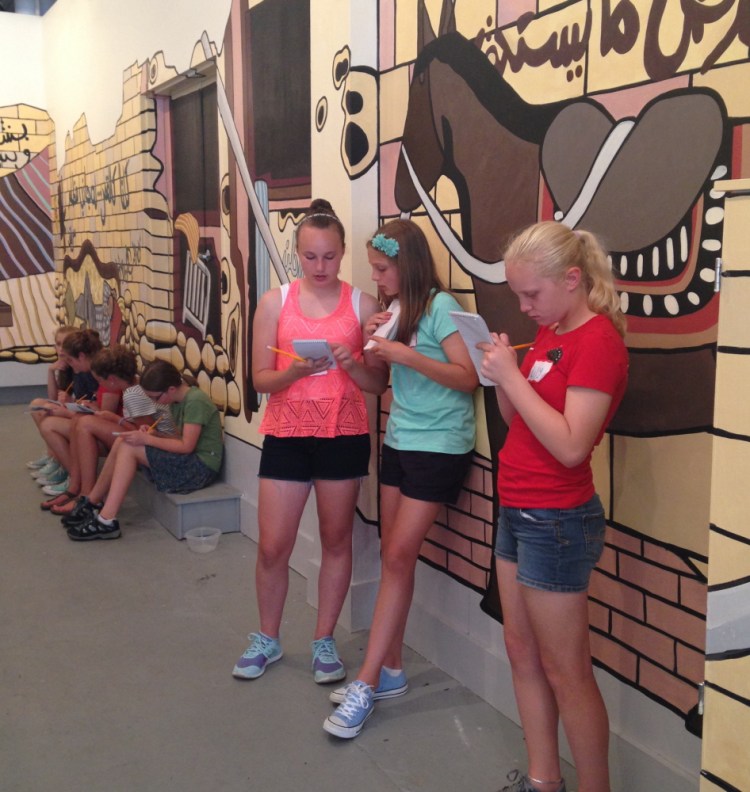 Students in The Telling Room summer camp on review writing work on their critiques of “We Are Staying,” a mural by Alina Gallo that was displayed at SPACE Gallery in Portland.