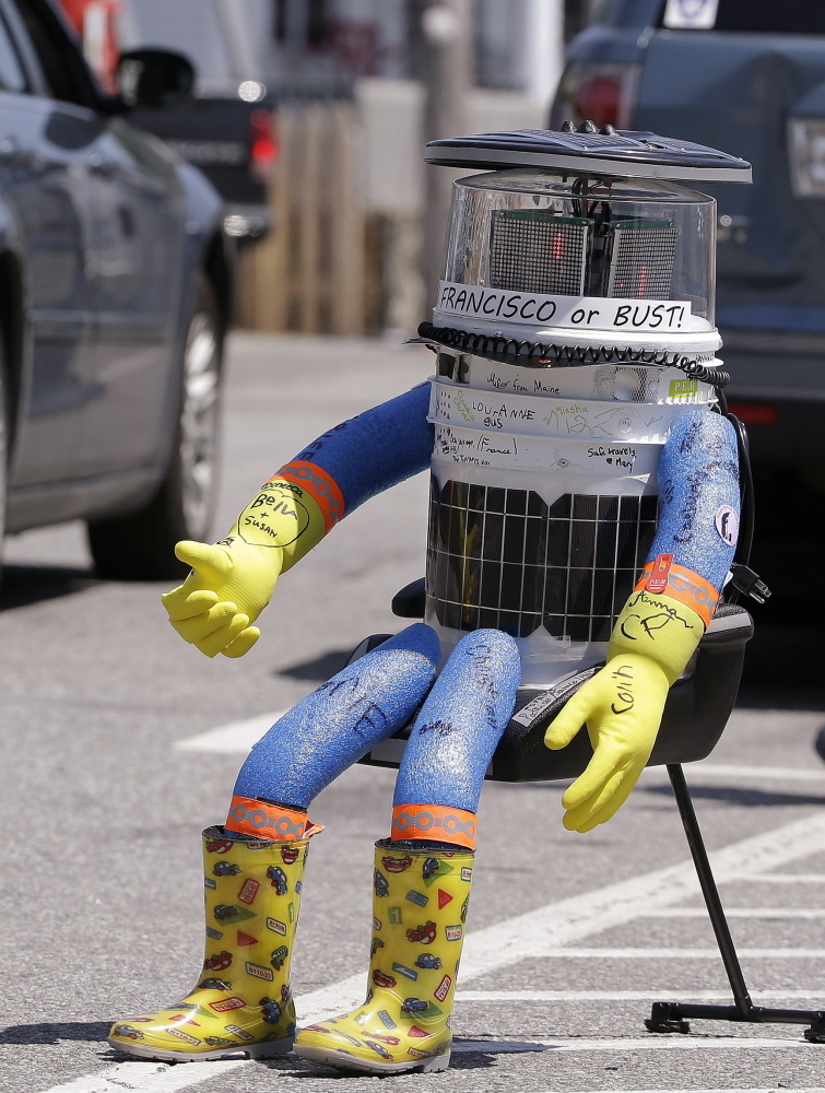 A car drives by HitchBOT, a hitchhiking robot, in Marblehead, Mass. The Associated Press