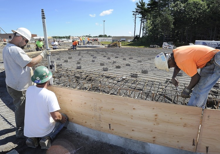 Chris Cormier, left, and Rick Podkowka build the concrete form as Bruce Ricks, right, installs the rebar that will be part of a garbage-eating power-generation plant  at Brunswick Landing.
