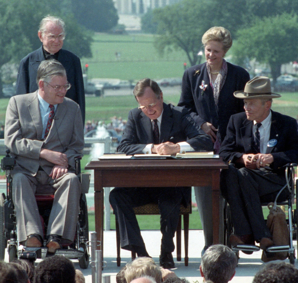 President George H.W. Bush signs the Americans with Disabilities Act during a ceremony at the White House on July 26, 1990. Joining the president are, from left, Evan Kemp, chairman of the Equal Opportunity Employment Commission; the Rev. Harold Wilke; Sandra Parrino, chairman of the National Council on Disability; and Justin Dart, chairman of The President’s Council on Disabilities.