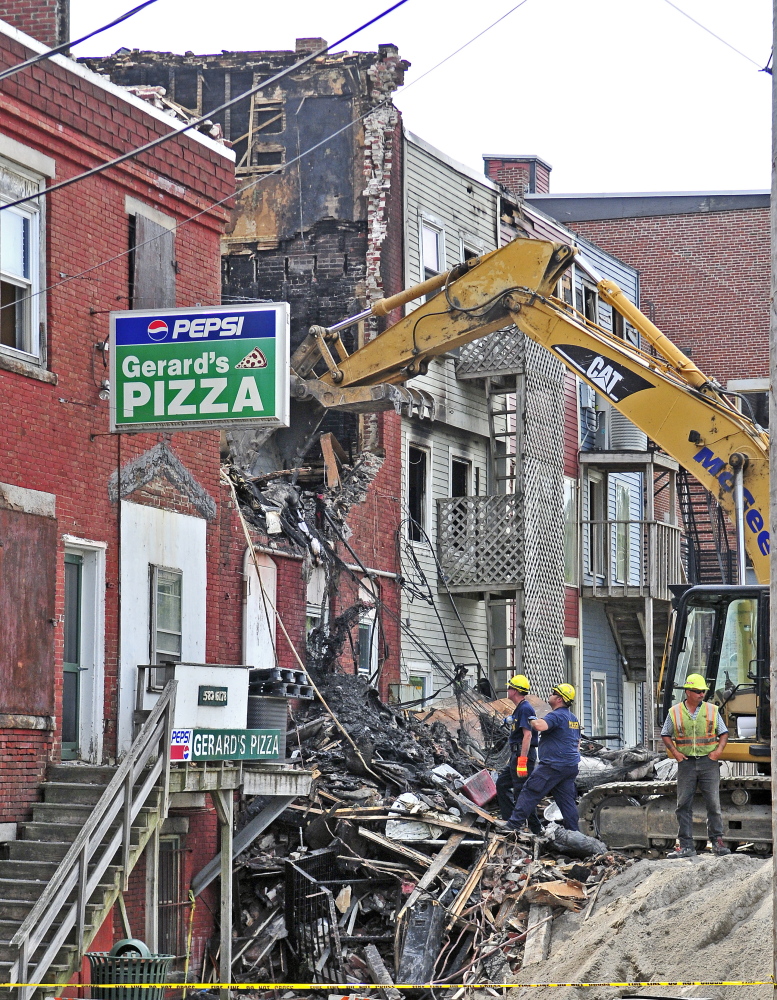An excavator is used to, investigate the scene of a major fire in downtown Gardiner the morning after it happened.