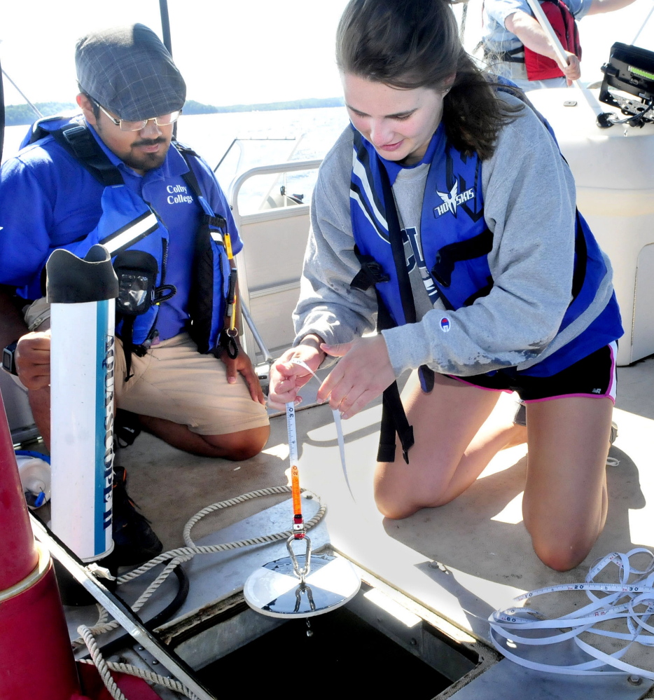Colby College student Ellie Irish, right, lowers a Secchi disk that measures water clarity as fellow student Sergio Madrigal prepares other equipment to determine water quality on Great Pond in Belgrade on Thursday.