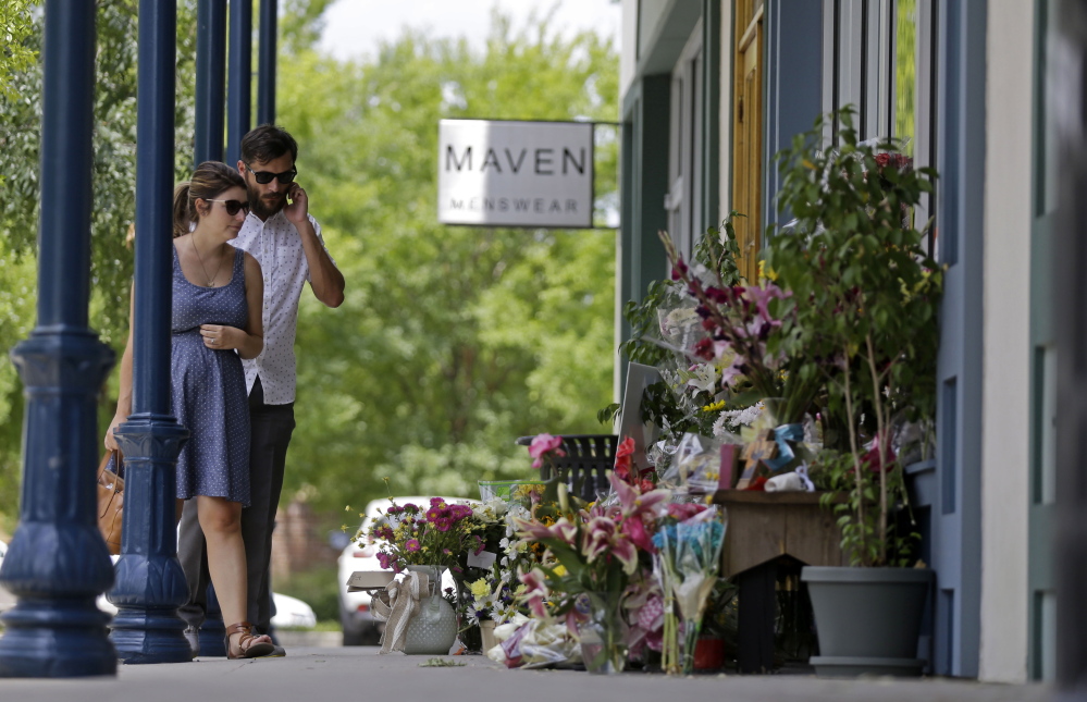 David and Sarah Flores, both of Lafayette, view flowers placed outside the Red Arrow Workshop on Sunday in Lafayette, La.. The store was owned by Jillian Johnson, who died when John Russell Houser stood up during Thursday night’s showing of “Trainwreck” and fired on the audience with a semi-automatic handgun.