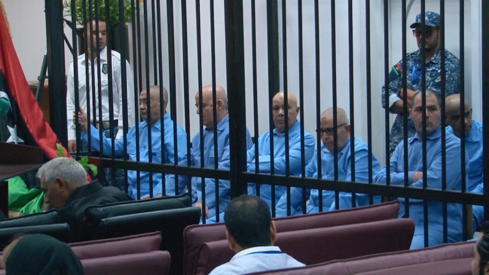 In this image made from AP video, former Libyan officials who served during Moammar Gadhafi’s era sit in the defendants’ cage during their trial for crimes committed during Libya’s 2011 uprising, in a courtroom in Tripoli, Libya, Tuesday.