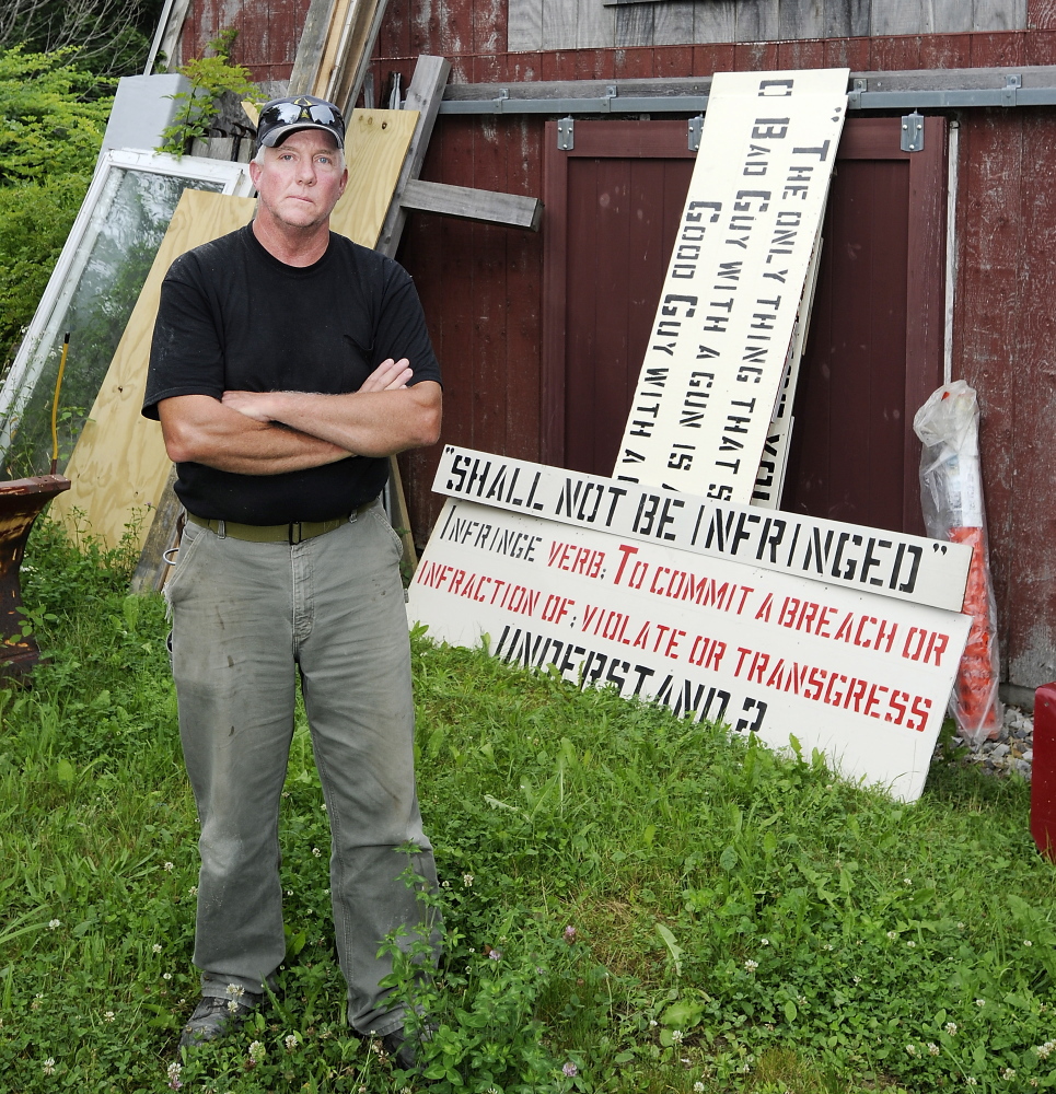 Linc Sample of Boothbay Harbor stands Tuesday with the next sign he plans to post in his yard. He says “half the people in town really don’t like my signs and don’t like me because of them.”
