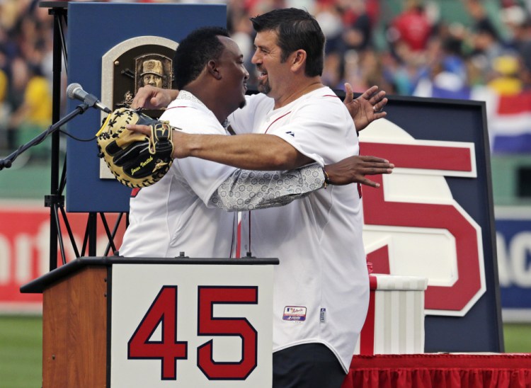 Baseball Hall of Fame member and former Boston Red Sox pitcher Pedro Martinez is embraced by former teammate Jason Varitek after his jersey was retired Tuesday at Fenway Park.
