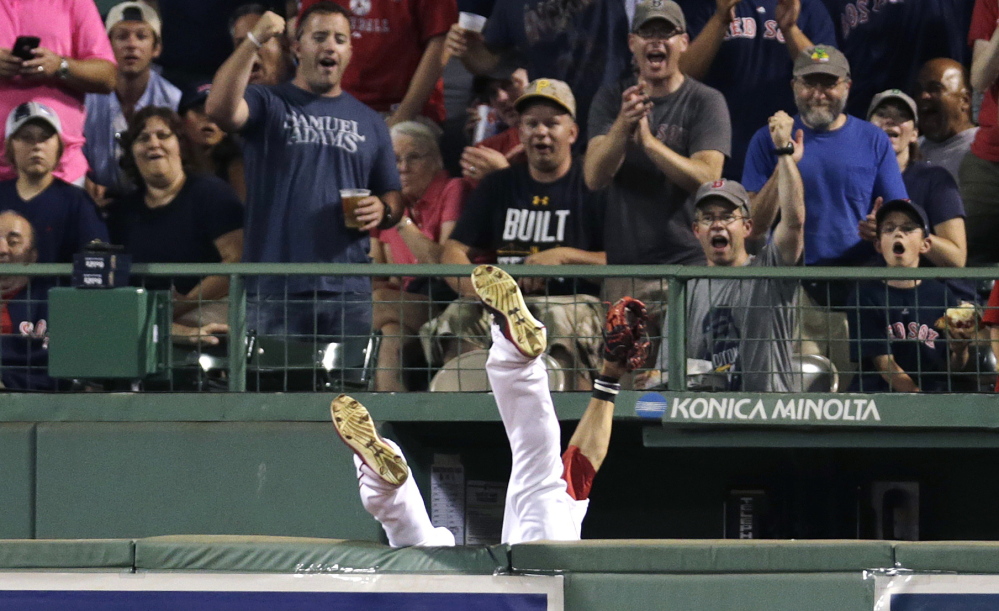 Boston Red Sox center fielder Mookie Betts flips over the bullpen wall while trying to field a drive by Chicago White Sox’s Jose Abreu during the sixth inning Tuesday at Fenway Park in Boston. Betts dropped the ball when he landed and umpires ruled the play a home run after video replay review.
