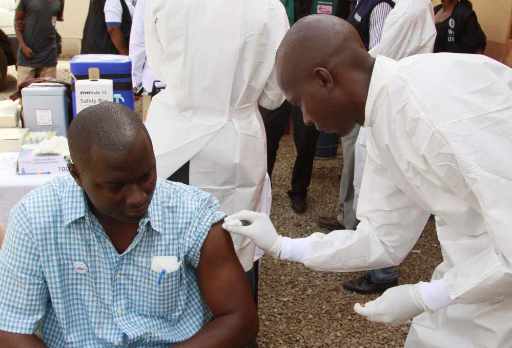 A health worker cleans a man’s arm before injecting him with a Ebola vaccine in Conakry, Guinea. The outbreak has killed 11,000 in Africa.