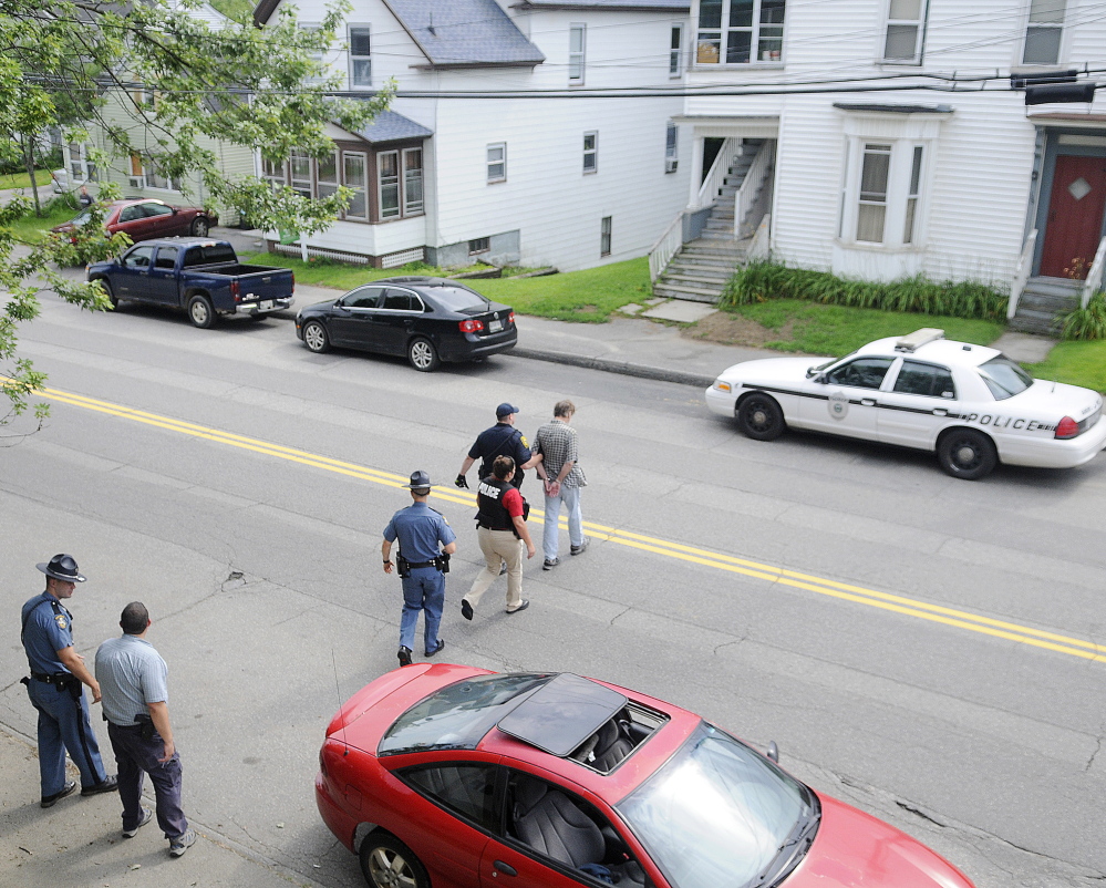 An Augusta police detective and other law enforcement personnel escort a man arrested on outstanding warrants to a waiting cruiser Thursday on Northern Avenue. State and county law enforcement officers accompanied Augusta police on walks through several neighborhoods in the city.
