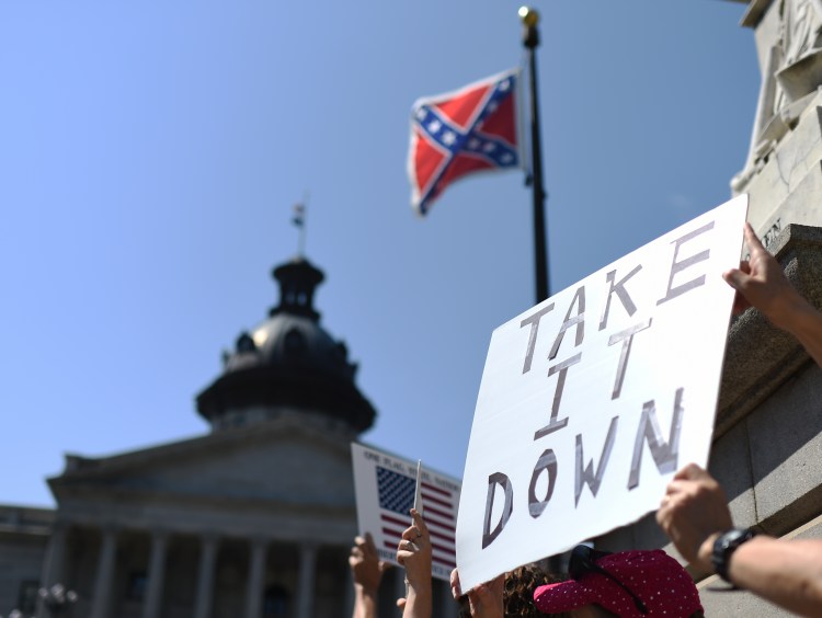 Protesters hold a sign during a rally to take down the Confederate flag at the South Carolina Statehouse, on June 23, 2015, in Columbia, S.C. For years, South Carolina lawmakers refused to revisit the Confederate flag on Statehouse grounds, saying the law that took it off the dome was a bipartisan compromise, and renewing the debate would unnecessarily expose divisive wounds. The Associated Press