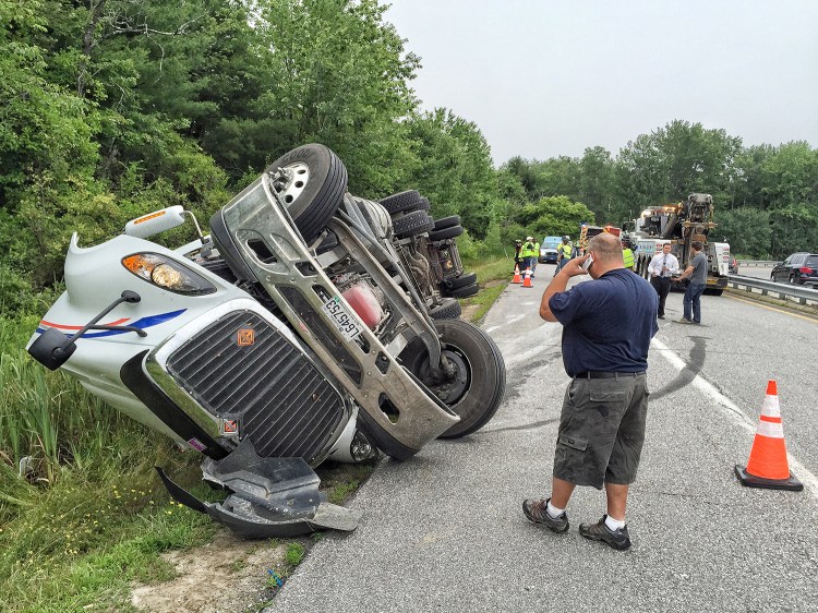 Marc Besner from Quebec province talks to his company after rolling his truck filled with peat moss on the Southbound off-ramp at exit 10 in Falmouth. Police say he was going over the speed limit of 25 mph for the off-ramp. Gordon Chibroski
