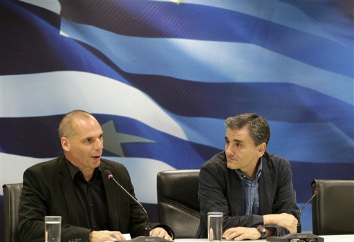 Outgoing Greek Finance Minister Yanis Varoufakis, left, speaks as the new Finance Minister, Euclid Tsakalotos, listens during a handover ceremony in Athens Monday. The Associated Press