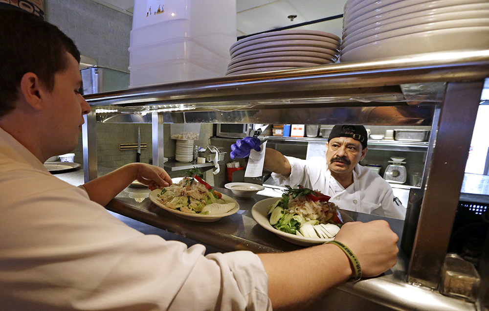 Cook Bulmaro Sosa  goes over a food order with server Zachary DeYoung at an Ivar's restaurant in Seattle. The Associated Press