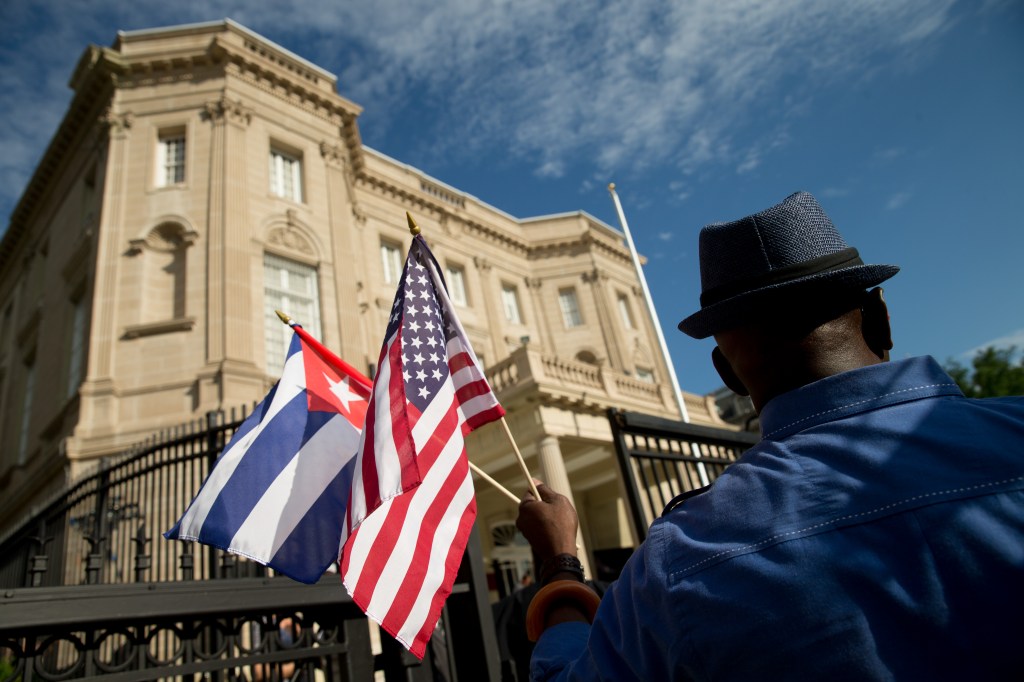 Edwardo Clark, a Cuban-American, holds an American flag and a Cuban flag as he celebrates outside the new Cuban embassy in Washington on Monday. The Associated Press