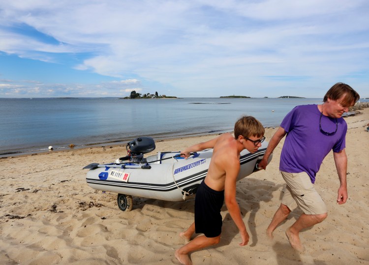 Keith McManus of Barrington, R.I., drags his inflatable boat up from the water with the help of his son Kieran, 13, after helping to rescue two men who had become stranded by the incoming tide between Hills Beach and Basket Island in Biddeford.
Derek Davis/Staff Photographer