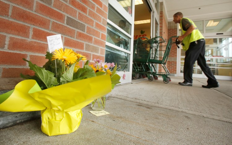 People placed flowers outside of the entrance to Shaw's supermarket in Saco on Thursday morning. Wendy Boudreau, 59, died after being stabbed  inside the store on Wednesday and police have charged Connor MacCalister, 31, with her murder. Gregory Rec/Staff Photographer