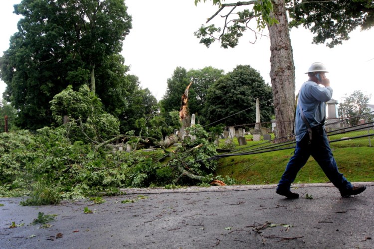 Central Maine Power Co. crewman Sam Pottle walks past debris that knocked out a row of power lines Saturday afternoon on Morton Street in Winthrop during a thunderstorm that hit Winthrop and nearby communities.