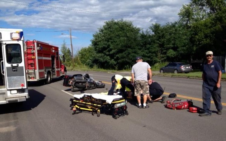 Emergency responders help a motorcyclist who was injured in a collision with a Jeep on College Avenue Thursday afternoon in Waterville.
