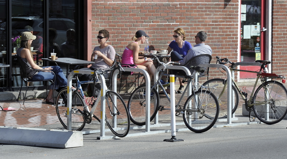 Patrons chat at tables next to a bike rack outside Arabica Coffee and Rosemont Market & Bakery on Commercial Street in Portland.
