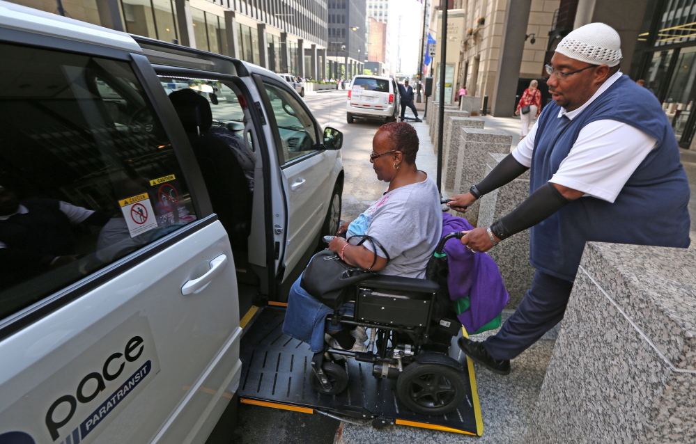 Driver Carl James helps Renita Freeman into his van as she leaves her job at the Ralph Metcalfe Federal Building in Chicago.