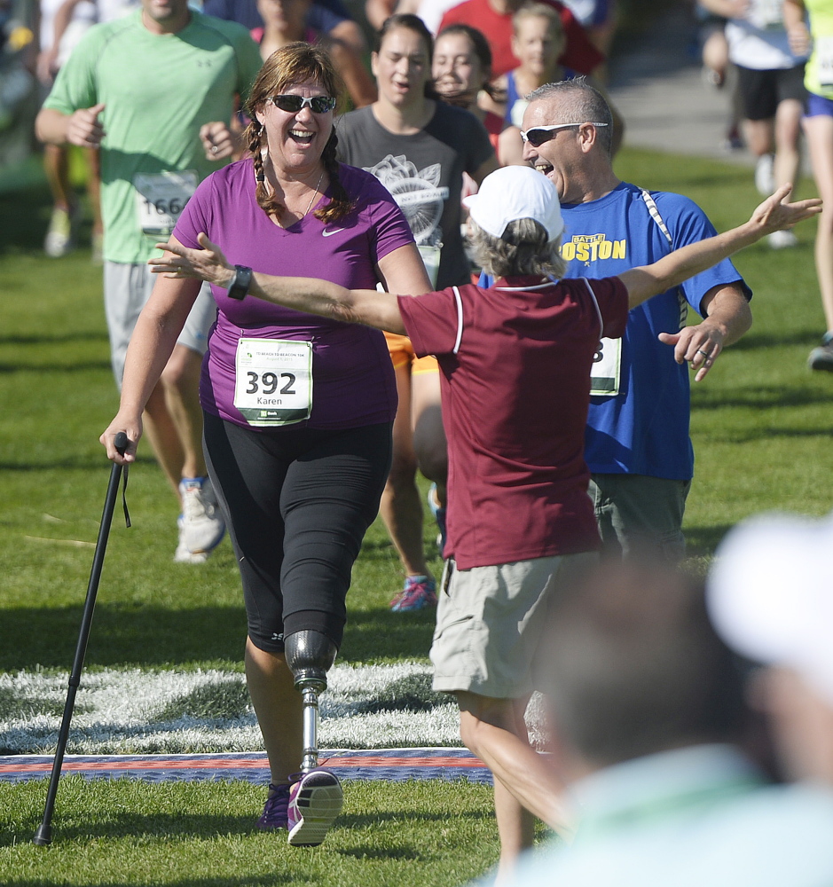 Karen Rand McWatters formerly of Westbrook, is greeted at the finish line by race founder Joan Benoit Samuelson after finishing the TD Beach to Beacon 10K Saturday. McWatters is a survivor of the 2013 Boston Marathon bombing, having lost the lower portion of her left leg.