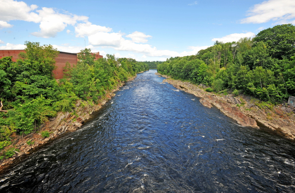 A section of the Kennebec River flows under the footbridge below the Weston Dam, where a railroad trestle used to be. The railroad bridge wreckage must be removed before a whitewater park planned for the river can be built.