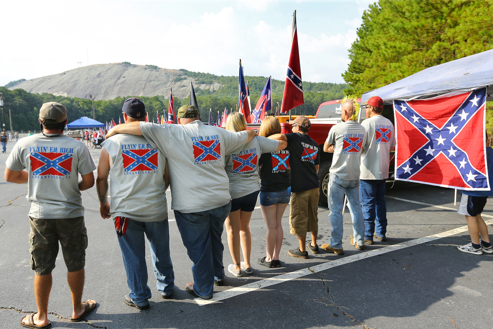 Members of the “Flyin’ Em High” group from Loganville wear shirts and hang flags while participating in a pro-Confederate flag rally at Stone Mountain Park in Stone Mountain, Ga., on Saturday.