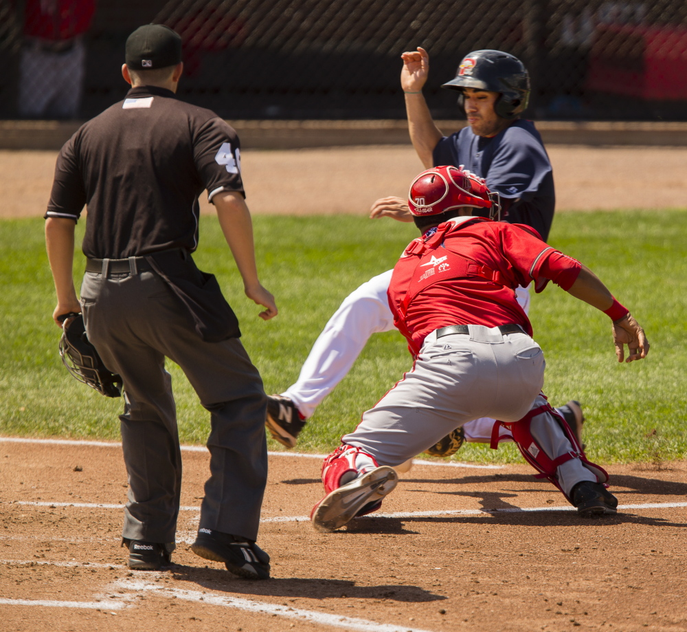 Carlos Asuaje of the Sea Dogs slides around the attempted tag by Harrisburg Senators catcher Pedro Severino to score a run Sunday during Portland’s 16-12 loss.