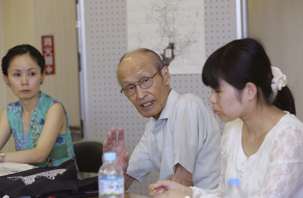 Shigeyuki Katsura, 84, center, a survivor of the Nagasaki atomic bombing, speaks with people who wish to learn and tell his story. He says he feels driven to recount his experience for as long as he lives.