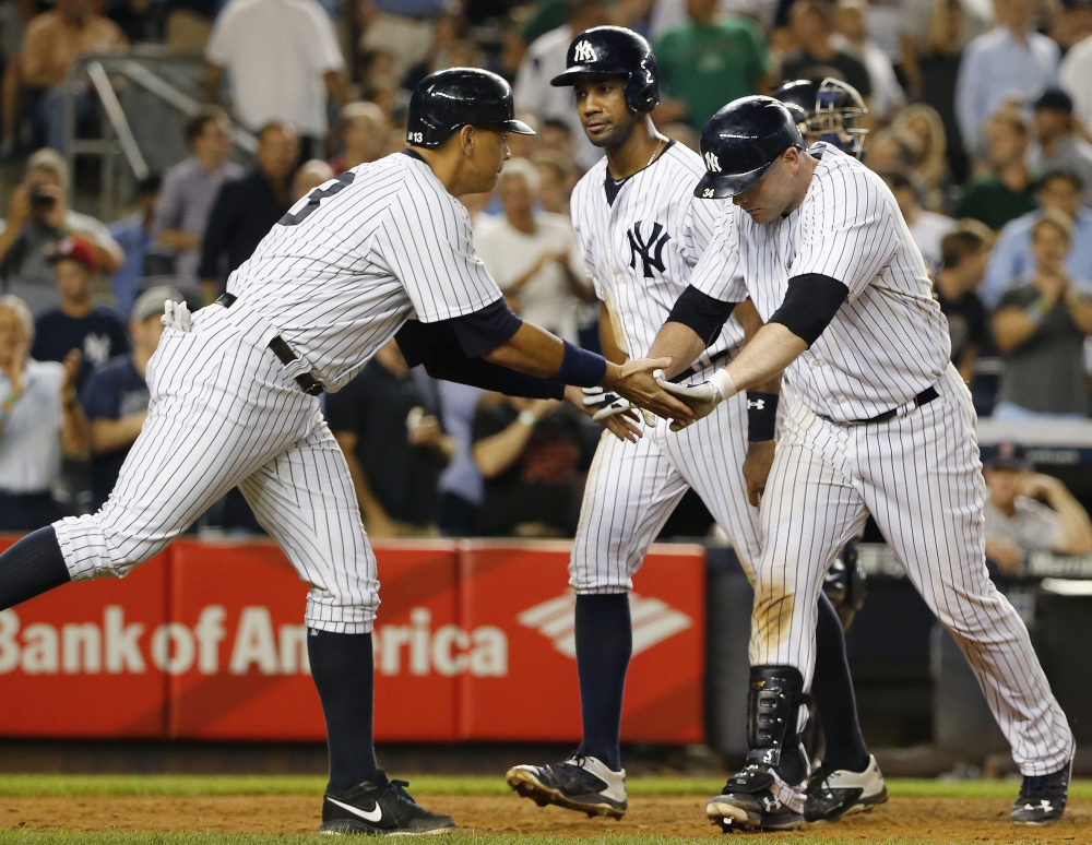 The Yankees’ Alex Rodriguez, left, celebrates with Brian McCann after Rodriguez and Chris Young, center, scored on McCann’s seventh-inning home run. Boston’s bullpen was ineffective in a 13-3 loss.
