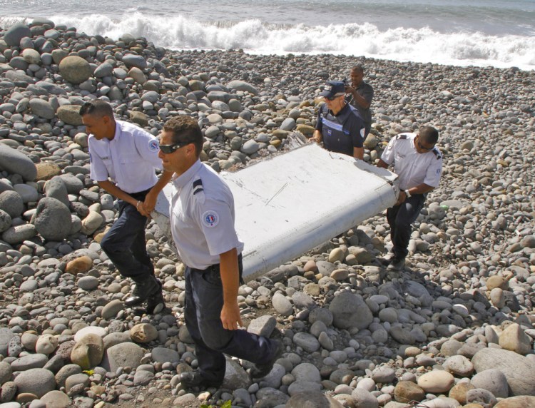 In this July 29, 2015 file photo, French police officers carry a piece of debris from a plane in Saint-Andre, Reunion Island.