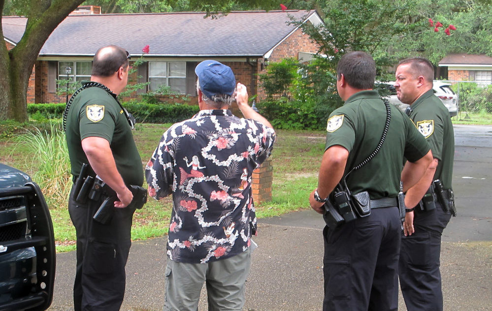 Escambia County Sheriff’s deputies talk with an unidentified man Wednesday outside the Pensacola-area home where three family members were found dead on July 28.