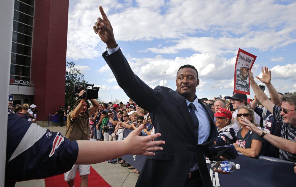 Former New England Patriots linebacker Willie McGinest acknowledges fans as he is introduced while being inducted into the Patriots Hall of Fame prior to a training session in Foxborough, Mass., on Wednesday.
